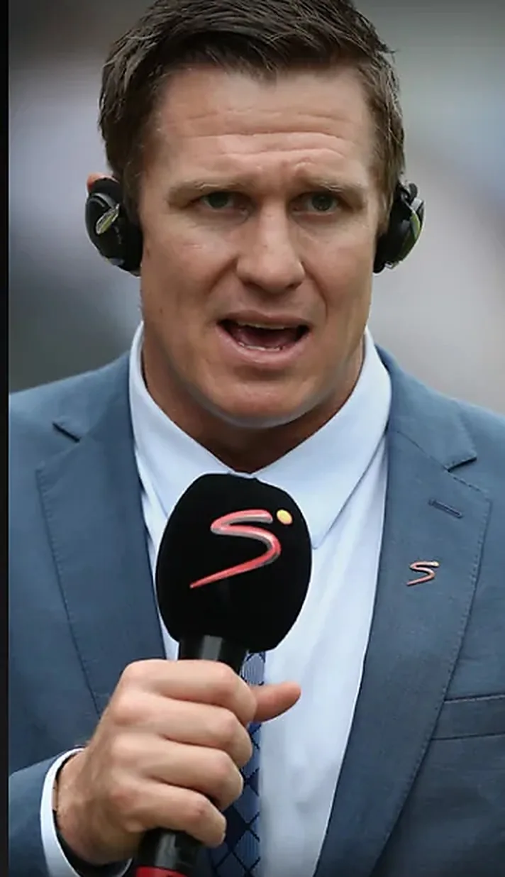 A sports presenter speaking into a microphone